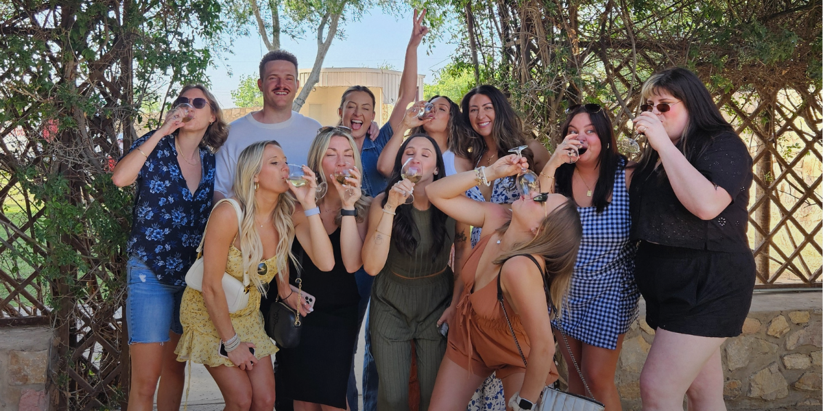 Friends celebrate a birthday posint for a photo drinking wine