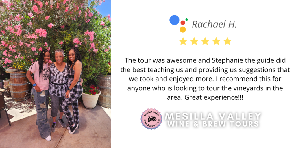 Three women pose in front of a wall of flowers at a winery